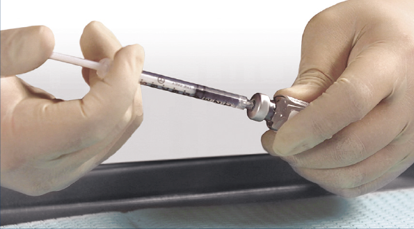 A physician holding a syringe fully inserted into a vial of XIAFLEX®