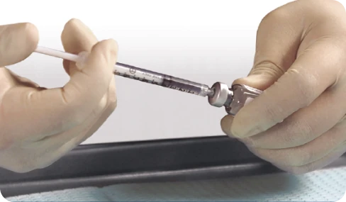 A healthcare professional slowly injecting the diluent into the XIAFLEX powder