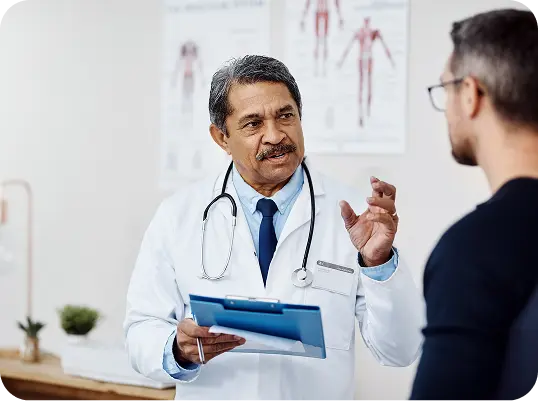 A male doctor consulting with a male patient in the exam room