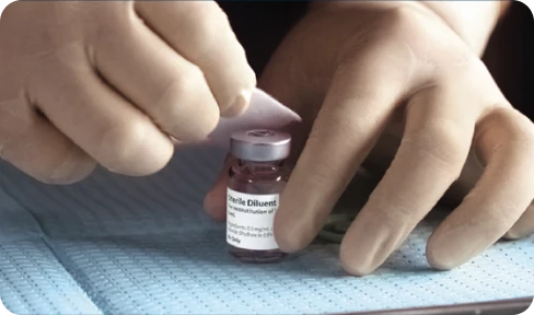 A healthcare professional removing the flip-off cap from a vial of XIAFLEX