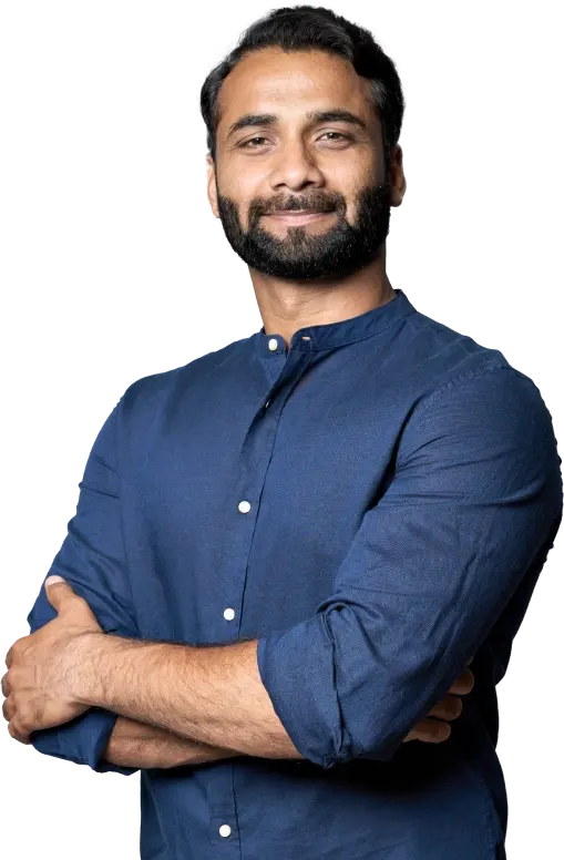 A man in a blue shirt standing confidently with his arms crossed and smiling at the camera